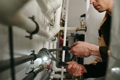 Technician inspecting commercial plumbing pipes in Menlo Park